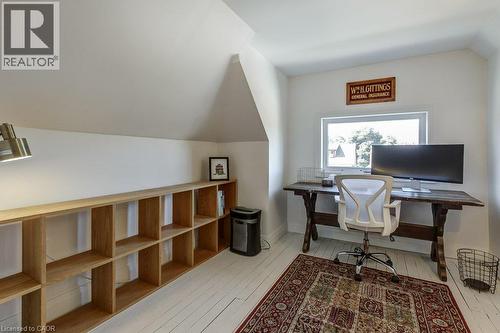 Attic space featuring sloped ceilings, a  wood-finish shelving unit, a window, and wood-finish flooring - 43 Rosslyn Avenue S, Hamilton, ON 