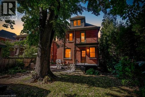 Brick exterior, dormer window, second-story balcony with metal railing, ground-level entrance with metal railing, mature trees - 43 Rosslyn Avenue S, Hamilton, ON 