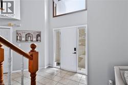 Entryway featuring a white door with a vertical window, transom window, and tile flooring - 