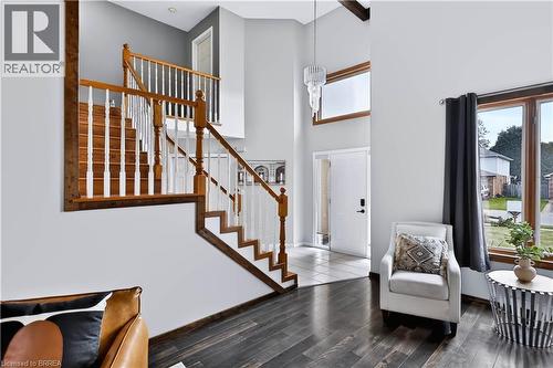 Two-story entry with wood-finish flooring, a traditional staircase with wood handrails, and a transom window above the entry door - 19 Hyslop Drive, Caledonia, ON 
