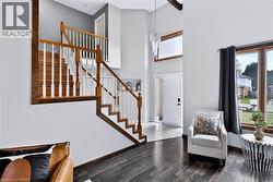 Two-story entry with wood-finish flooring, a traditional staircase with wood handrails, and a transom window above the entry door - 