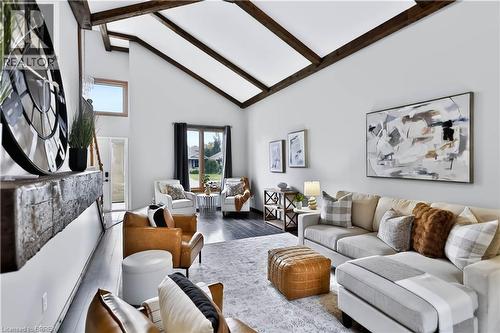 Vaulted ceiling with exposed wood beams, wood-finish flooring, large windows, and a built-in fireplace mantel - 19 Hyslop Drive, Caledonia, ON 