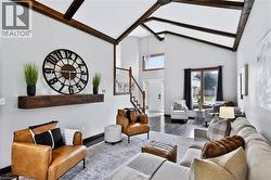 Vaulted ceilings with exposed wood beams, dark wood-finish flooring, staircase with wood handrail and white spindles, transom window, and a large picture window - 