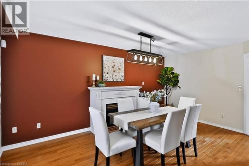 Wood-finish flooring, white decorative mantel, and a modern linear chandelier - 19 Hyslop Drive, Caledonia, ON 