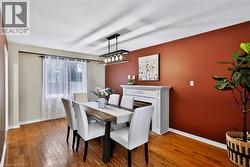 Hardwood flooring, decorative fireplace, modern lighting fixture, window with drapes, and a distinct accent wall - 