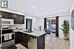 Kitchen featuring dark wood cabinetry, stainless steel appliances, a subway tile backsplash, and light-toned countertops - 