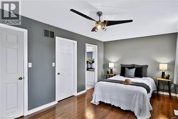 Wood-finish flooring, neutral grey walls, white trim, and a ceiling fan with integrated lighting - 