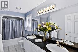 Double vanity with undermount sinks, black countertop, white cabinetry, and large wall-mounted mirror - 