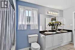 Double vanity with white cabinetry, dual sinks, black countertop, and an expansive wall mirror - 