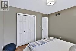 Hardwood-style flooring, white bi-fold closet doors, white interior door with round hardware, neutral wall paint, and a semi-flush mount ceiling light - 