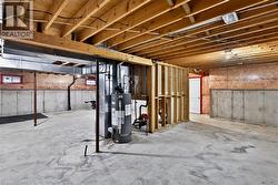 Unfinished basement with exposed ceiling joists, concrete flooring, and partial wall framing - 
