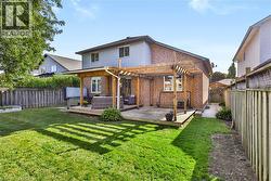 Brick and siding exterior with a wooden deck, a wooden pergola, and a grassy yard - 