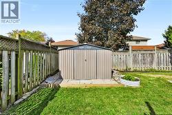 Expansive backyard featuring a manicured lawn, a metal storage shed on a concrete pad, and full perimeter fencing - 