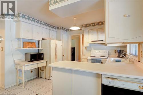 White cabinetry, tiled flooring, built-in desk, and a double basin sink - 8 Bonnylyn Drive, Kitchener, ON 