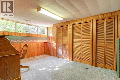 Wood-paneled walls featuring built-in cabinetry, multiple louvered bifold doors, and a drop ceiling with integrated lighting - 8 Bonnylyn Drive, Kitchener, ON 