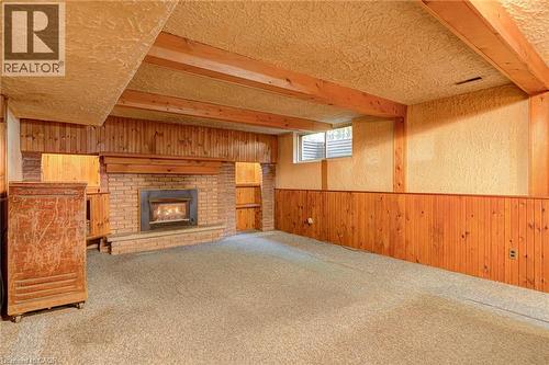 Brick fireplace with hearth, wood paneling, wood-beamed ceiling, and built-in shelving - 8 Bonnylyn Drive, Kitchener, ON 