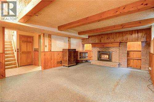 Brick fireplace with an integrated firebox and built-in shelving, wood paneling, exposed wood beams, and a carpeted floor - 8 Bonnylyn Drive, Kitchener, ON 