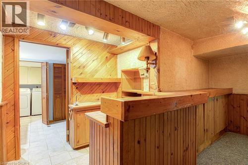Wood-paneled wet bar with built-in cabinetry, upper shelving, and track lighting - 8 Bonnylyn Drive, Kitchener, ON 