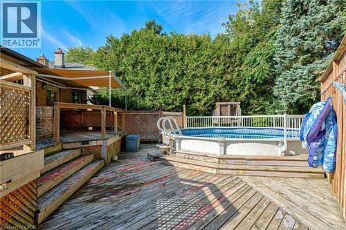 Multi-level wooden deck with an above-ground pool, a retractable awning, and a privacy fence - 8 Bonnylyn Drive, Kitchener, ON 