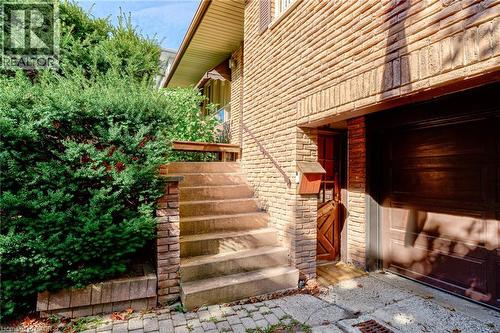 Brick exterior with a brown garage door, concrete steps, and a metal handrail - 8 Bonnylyn Drive, Kitchener, ON 
