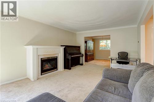 Built-in fireplace with a white mantel, light-colored carpeting, crown molding, and an open entryway to an additional room - 8 Bonnylyn Drive, Kitchener, ON 