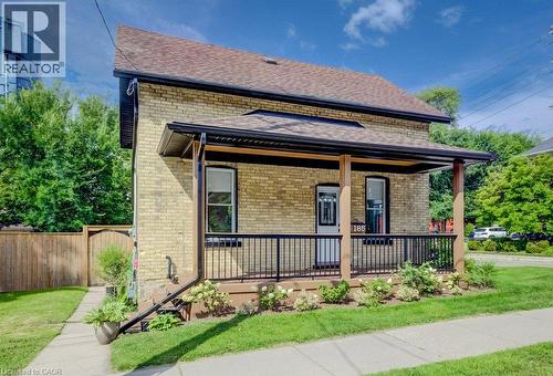Brick exterior with a covered porch, dark brown railings, and a brown shingle roof - 185 Strange Street, Kitchener, ON - Outdoor