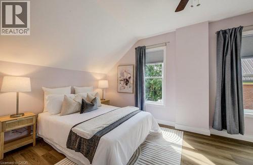 Sloped ceiling with recessed lighting, wood-finish flooring, two windows with window treatments, and a ceiling fan - 185 Strange Street, Kitchener, ON - Indoor Photo Showing Bedroom