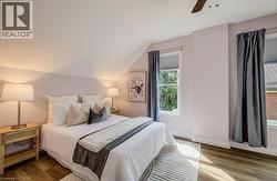 Sloped ceiling with recessed lighting, wood-finish flooring, two windows with window treatments, and a ceiling fan - 