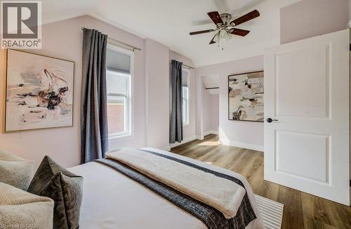 Wood-finish flooring, multiple windows with blinds, ceiling fan, and a paneled door - 185 Strange Street, Kitchener, ON - Indoor Photo Showing Bedroom