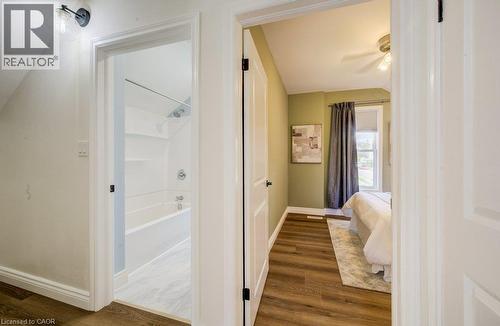 Wood-finish flooring throughout, white interior doors, and a bathroom featuring a shower-tub combination with a wall-mounted showerhead - 185 Strange Street, Kitchener, ON - Indoor Photo Showing Other Room