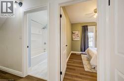 Wood-finish flooring throughout, white interior doors, and a bathroom featuring a shower-tub combination with a wall-mounted showerhead - 
