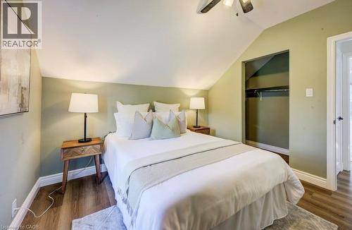 Angled ceiling with a ceiling fan, wood-finish flooring, recessed closet, and built-in shelving - 185 Strange Street, Kitchener, ON - Indoor Photo Showing Bedroom