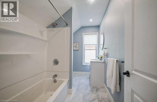 Tub/shower combination with a curved shower rod, vanity with an integrated sink, window with privacy blind, and recessed lighting - 185 Strange Street, Kitchener, ON - Indoor Photo Showing Bathroom