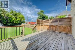 Expansive wooden deck with slatted privacy fencing, leading to a grassed yard with perimeter wood fencing - 