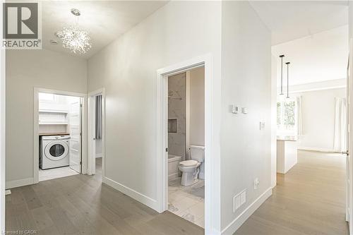 Laundry area with built-in shelving, wood-finish flooring, recessed lighting, and a modern chandelier - 7966 Fallon Drive Unit# 18, Lucan Biddulph (Twp), ON - Indoor Photo Showing Laundry Room