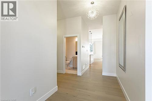 Light wood-finish flooring, recessed lighting, and a contemporary chandelier illuminate this hallway - 7966 Fallon Drive Unit# 18, Lucan Biddulph (Twp), ON - Indoor Photo Showing Other Room