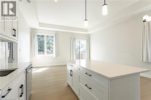 White shaker cabinetry, light wood-finish flooring, recessed lighting, kitchen island with countertop, and modern pendant lighting fixtures - 7966 Fallon Drive Unit# 18, Lucan Biddulph (Twp), ON - Indoor Photo Showing Kitchen