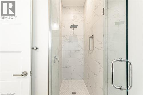 Walk-in shower with full-height tile surround, rain shower head, built-in niche, and glass enclosure with chrome hardware - 7966 Fallon Drive Unit# 18, Lucan Biddulph (Twp), ON - Indoor Photo Showing Bathroom