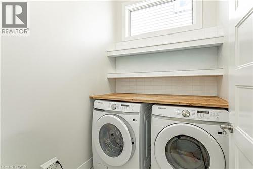 Wood-finish countertop, white subway tile backsplash, and built-in shelving - 7966 Fallon Drive Unit# 18, Lucan Biddulph (Twp), ON - Indoor Photo Showing Laundry Room
