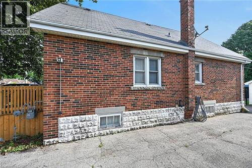 Brick exterior with stone foundation detailing, multiple windows, and a prominent brick chimney - 75 Barons Avenue S, Hamilton, ON 