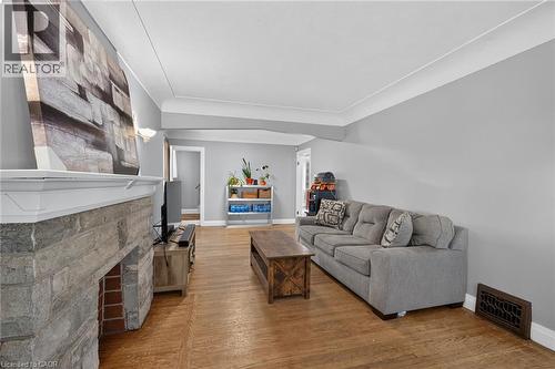 Stone-clad fireplace with a white mantel, wood-finish flooring, and light gray wall paint - 75 Barons Avenue S, Hamilton, ON 