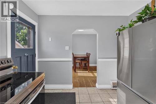 Modern stainless steel refrigerator and range, tiled flooring, cased opening, and a Dutch door - 75 Barons Avenue S, Hamilton, ON 