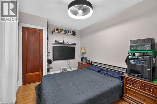Wood-finish flooring, light grey wall paint, and a dark wood door with textured glass paneling - 75 Barons Avenue S, Hamilton, ON 