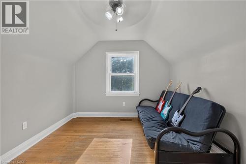 Sloped ceiling design, light neutral wall paint, wood-finish flooring, white trim, and a ceiling fan with integrated lighting - 75 Barons Avenue S, Hamilton, ON 
