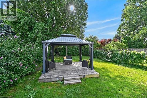 Expansive backyard featuring a wood-decked gazebo with a metal roof, mature trees, green lawn, and established landscaping - 75 Barons Avenue S, Hamilton, ON 