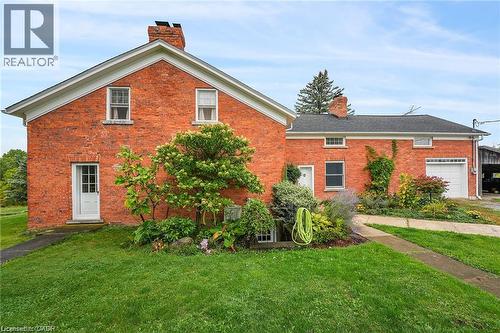 Brick exterior with white trim, established landscaping, attached garage with a white door, and an asphalt shingle roof - 2432 Seburn Road, Fonthill, ON - Outdoor With Exterior