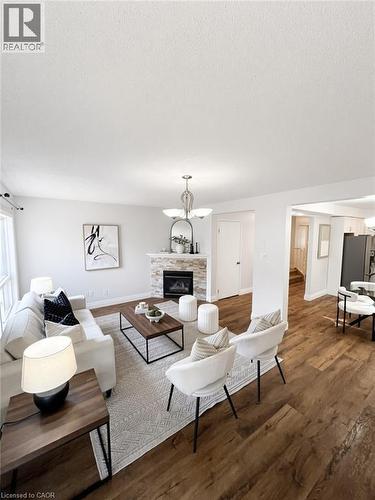Wood-finish flooring, recessed lighting, and a stone-clad fireplace with a hearth - 765 Angler Way, Waterloo, ON - Indoor Photo Showing Living Room With Fireplace