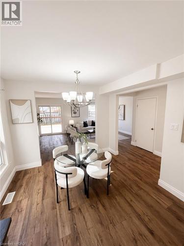 Wood-finish flooring throughout, bright white walls, recessed ceiling, modern chandelier, and sliding glass patio doors - 765 Angler Way, Waterloo, ON - Indoor