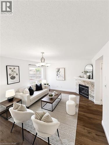 Wood-finish flooring, white walls, stone-faced fireplace with hearth, and a ceiling fan with integrated lighting - 765 Angler Way, Waterloo, ON - Indoor Photo Showing Living Room With Fireplace