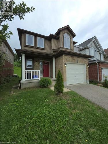 Two-story residence featuring brick and siding exterior, arched dormer window, covered porch with white columns and railing, and an attached garage with a paved driveway - 998 Mapleridge Street, London, ON - Outdoor With Deck Patio Veranda With Facade